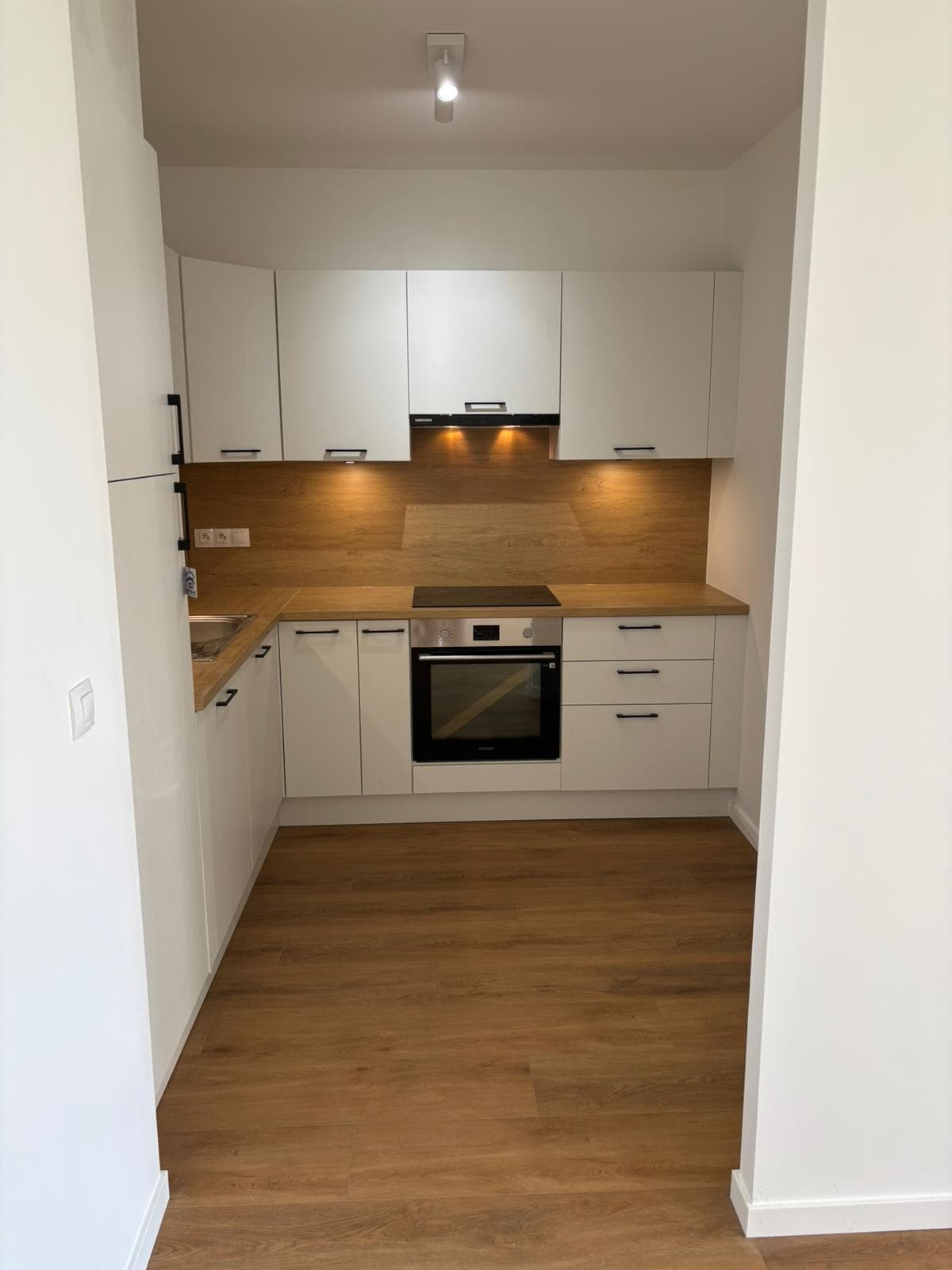Witte gerenoveerde keuken met houten achterwand en ingebouwde oven, Anderlecht